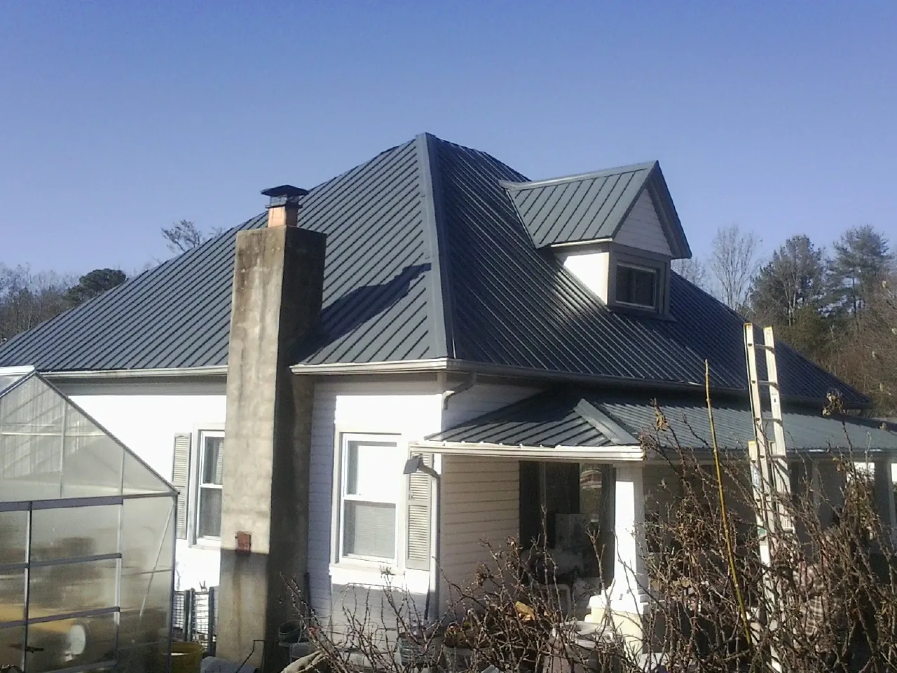 Dark blue standing seam metal roof on a white farmhouse with dormer — Slate & Tile Roof Repair by Roofing Brothers in Indian Valley