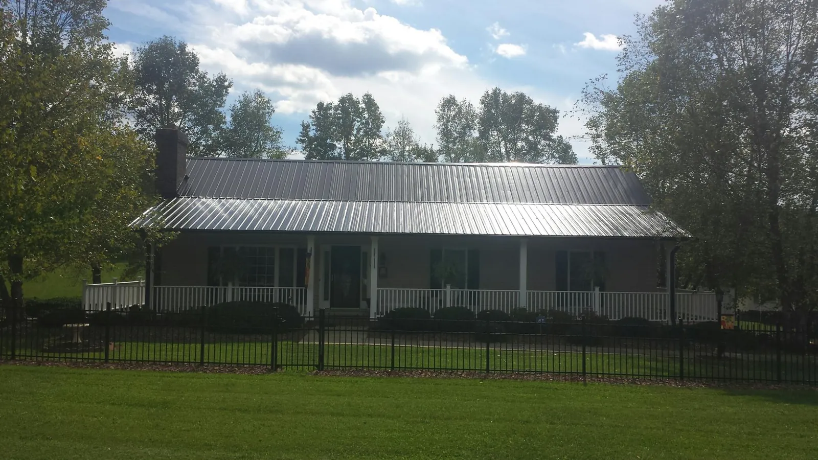 Gray metal roof on a brick ranch with a full width front porch — Gutter Guard Installation work by our crew in Indian Valley