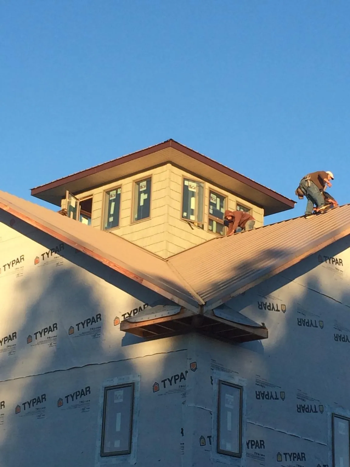 Roofers working around a rooftop cupola on a new metal roof at sunset — Roof Waterproofing in Indian Valley by Roofing Brothers